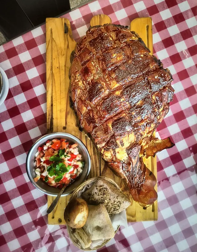 Bondiola braseada con salsa criolla, servida en tabla